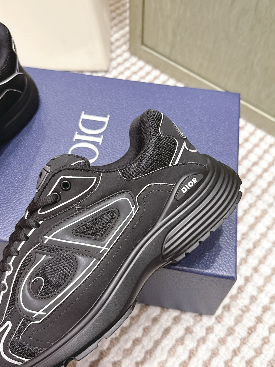 Black lace-up sneaker close-up with Dior logo, white trim, and textured panels