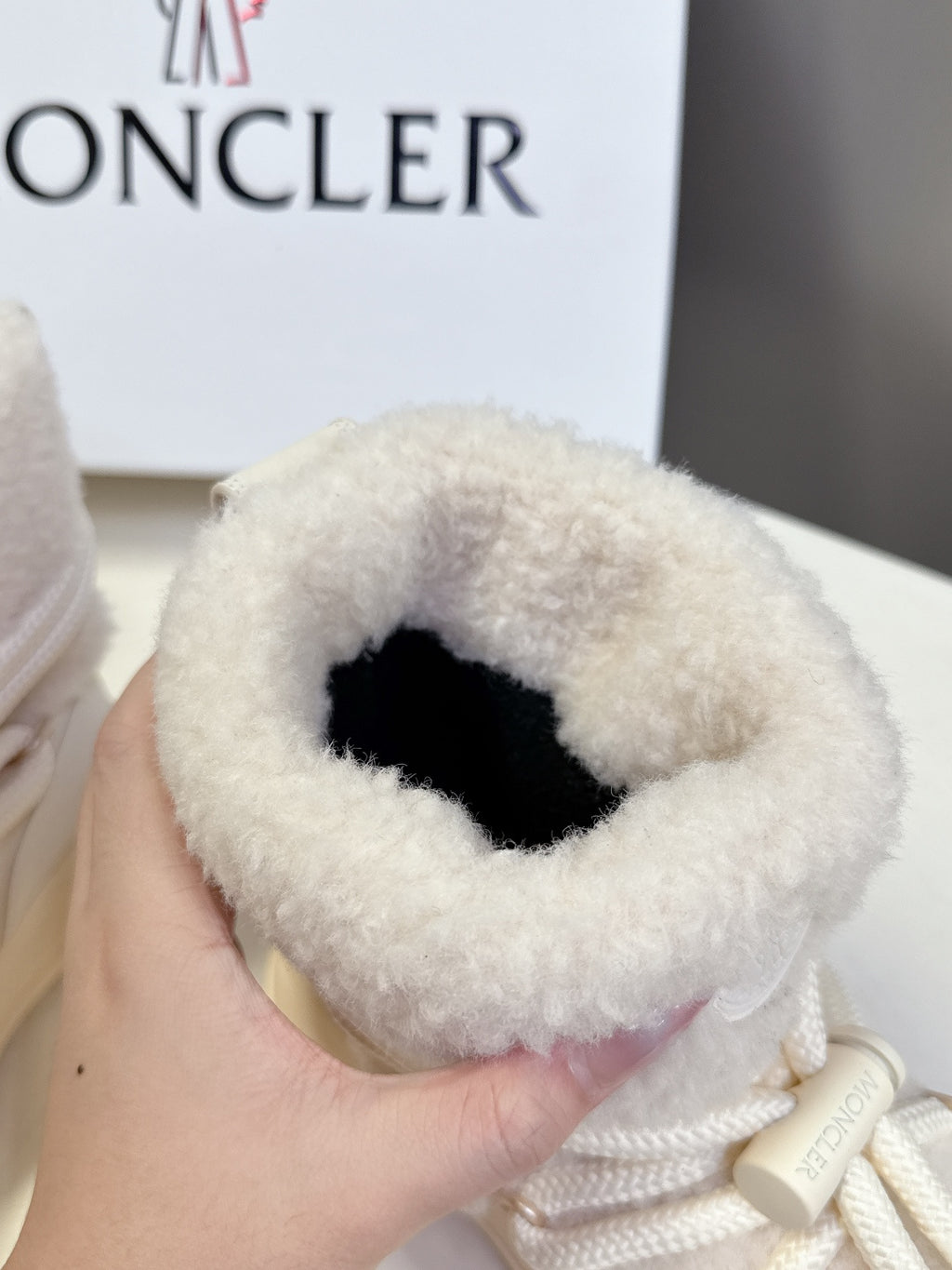 Cream fur-lined sneaker held in hand, showing black inner lining