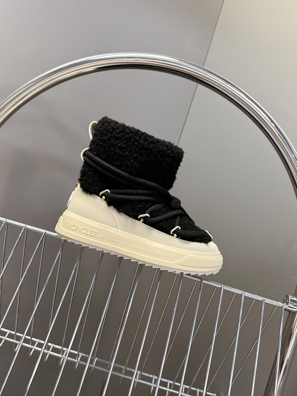 Moncler luxury shoes: black sherpa boot with cream sole, side view on display
