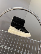 Moncler luxury shoes: black sherpa boot with cream sole, side view on display