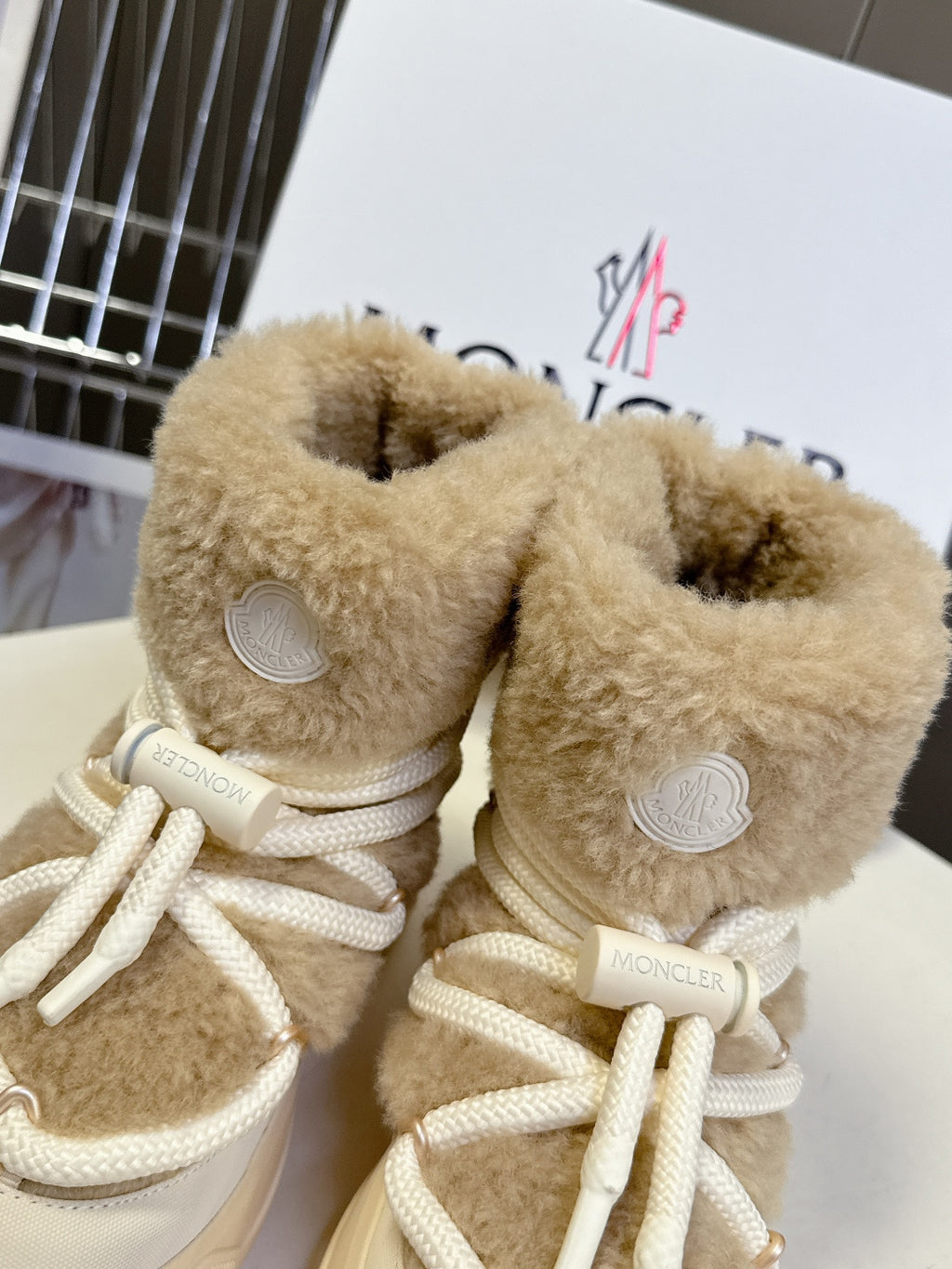 Beige shearling lace-up boots with circular emblem patches and white laces