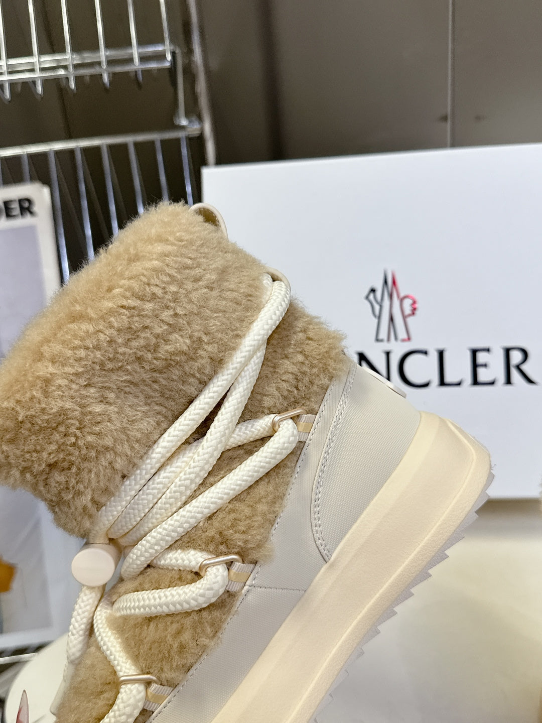 Beige shearling lace-up boot close-up with white laces and round side logo