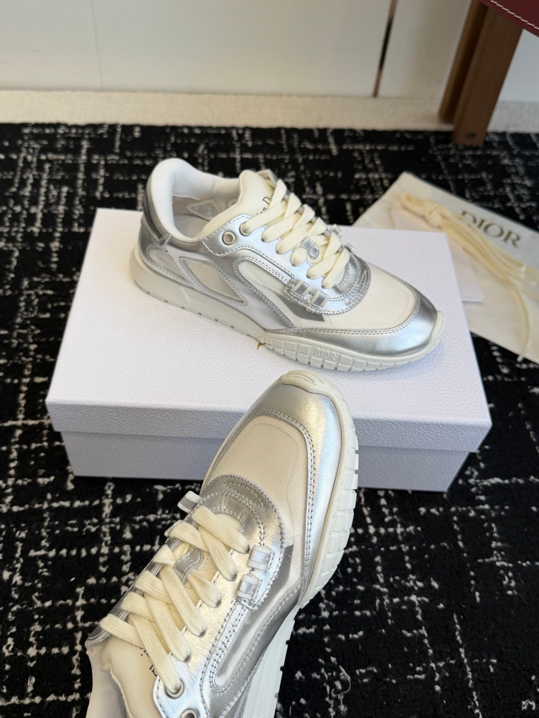 White and silver Dior low-top sneakers, front and side views on display