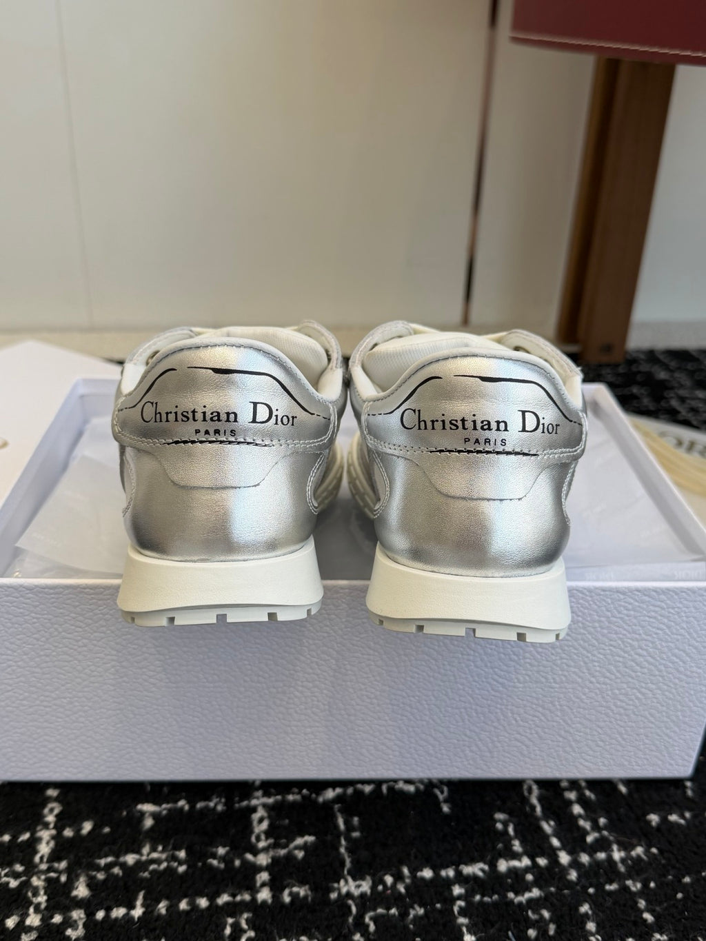 Pair of silver Dior low-top sneakers, rear view on box with branding