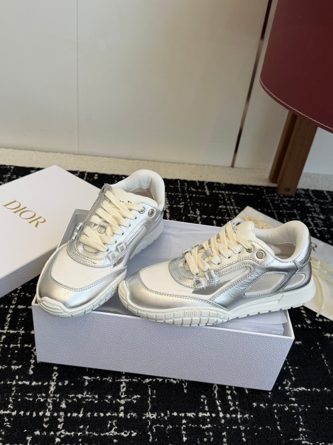 White and silver Dior low-top sneakers on box, angled front view