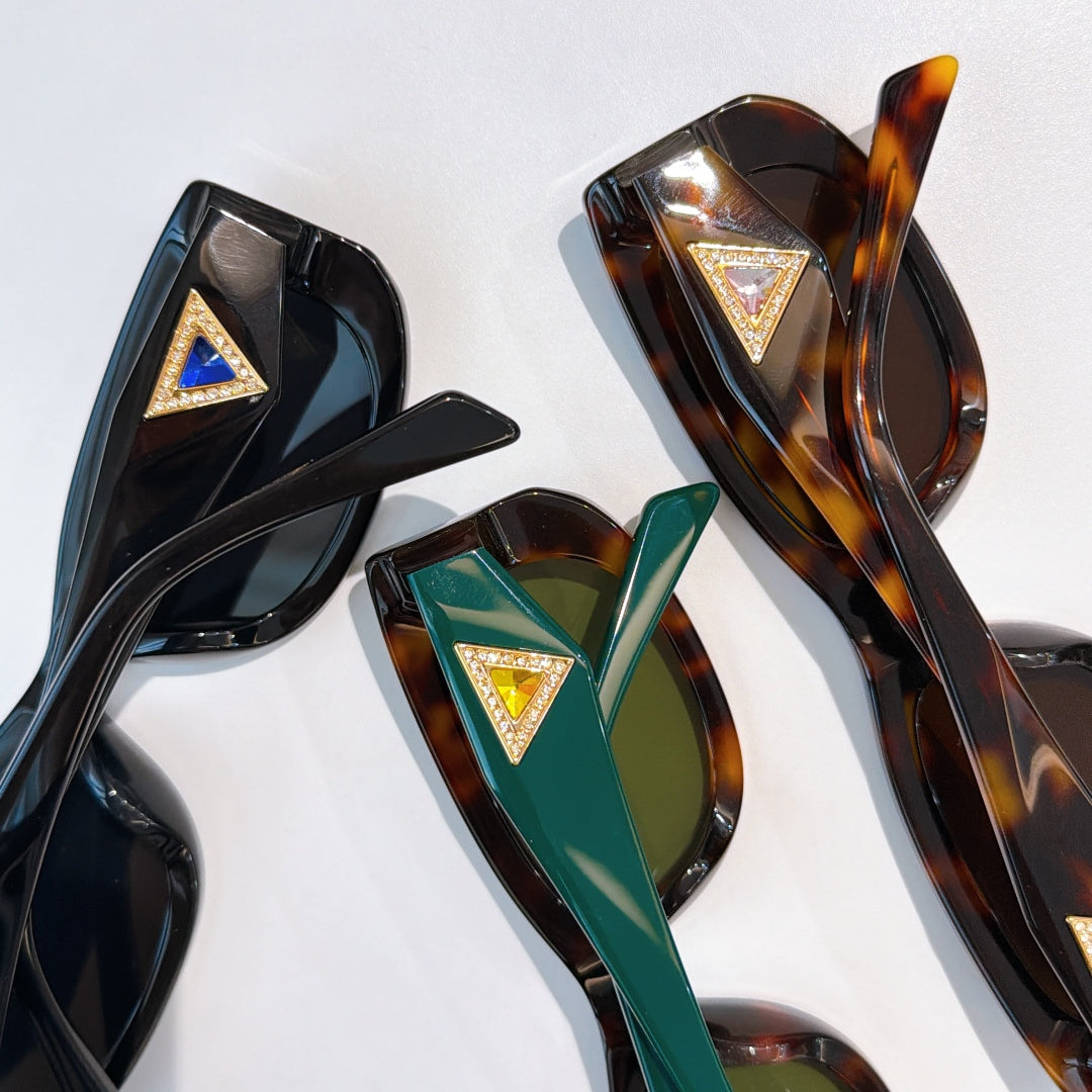 Close-up of sunglasses frames with gold triangle logos: black, dark brown, and green.