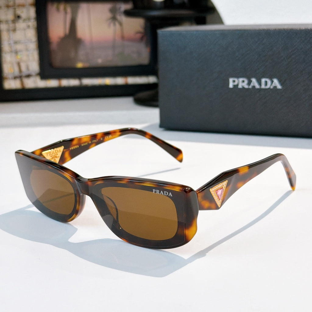 Sunglasses with amber tortoiseshell frame and brown lenses, gold triangle logo at temples.