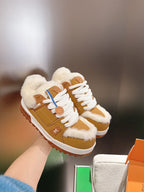 Unisex tan-and-white fur-trimmed sneakers with white laces, held above a shoebox