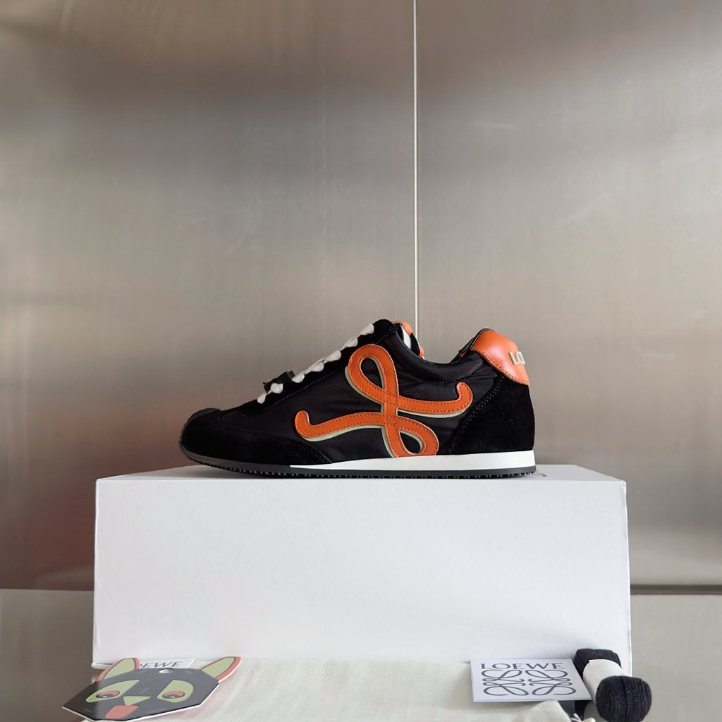 Unisex black low-top sneakers with orange emblem and white laces