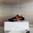 Unisex black low-top sneakers with orange emblem and white laces