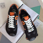 Unisex black sneakers with orange emblem and white laces, front and heel view