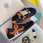 Unisex black sneakers with orange emblem, white laces, and orange heel trim
