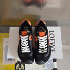Unisex black sneakers with orange trim, white laces, and logo on tongue