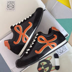 Unisex black sneakers with orange emblem, white laces, and textured sole