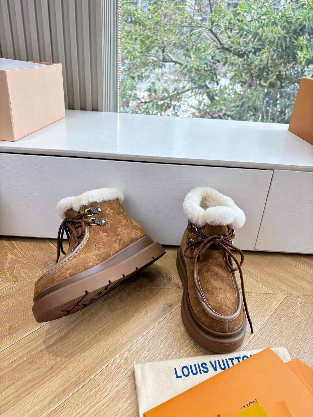 Louis Vuitton lace-up ankle boots, brown monogram suede with white shearling trim.