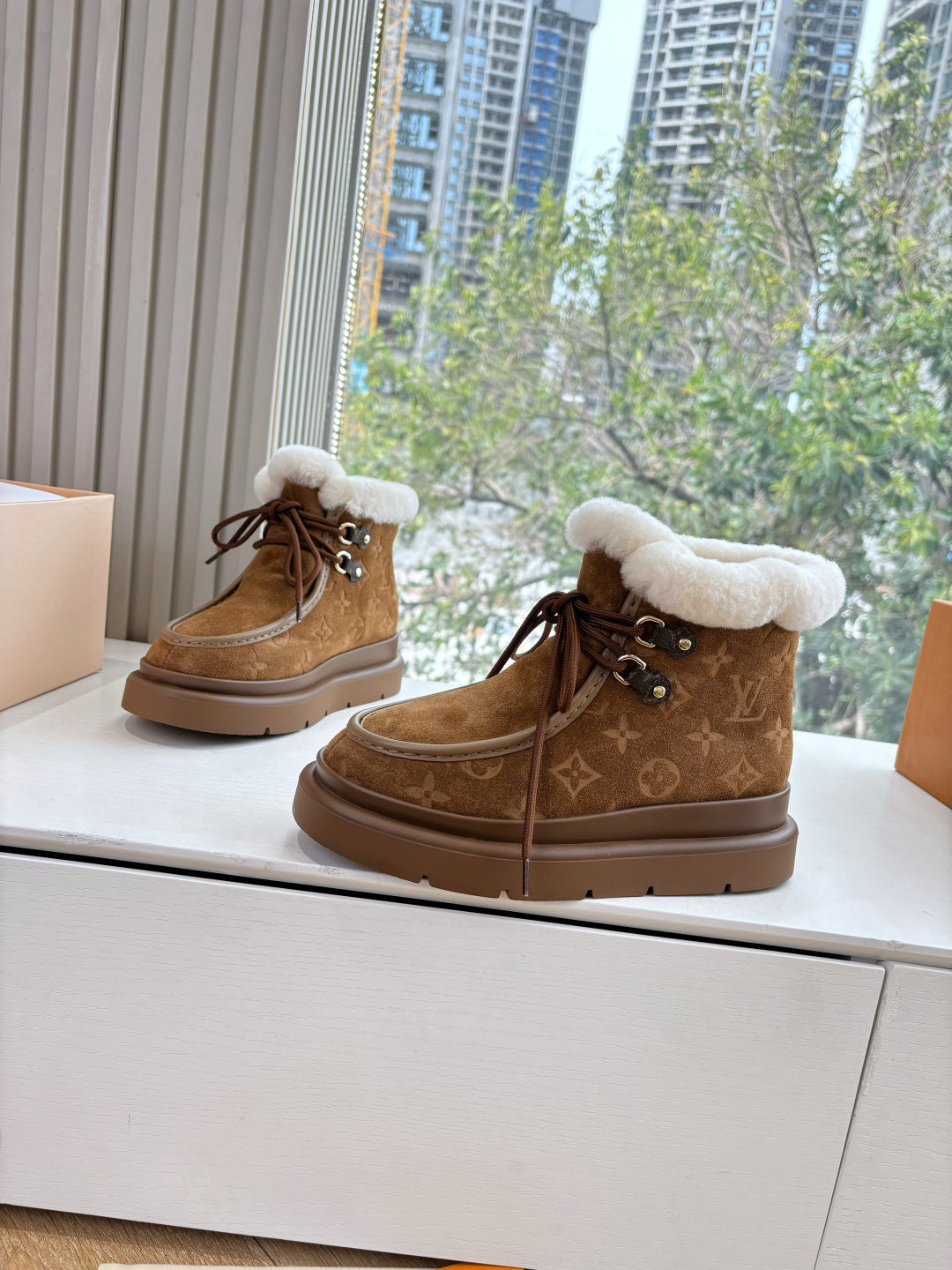 Louis Vuitton lace-up ankle boots, brown monogram upper with white shearling cuff.