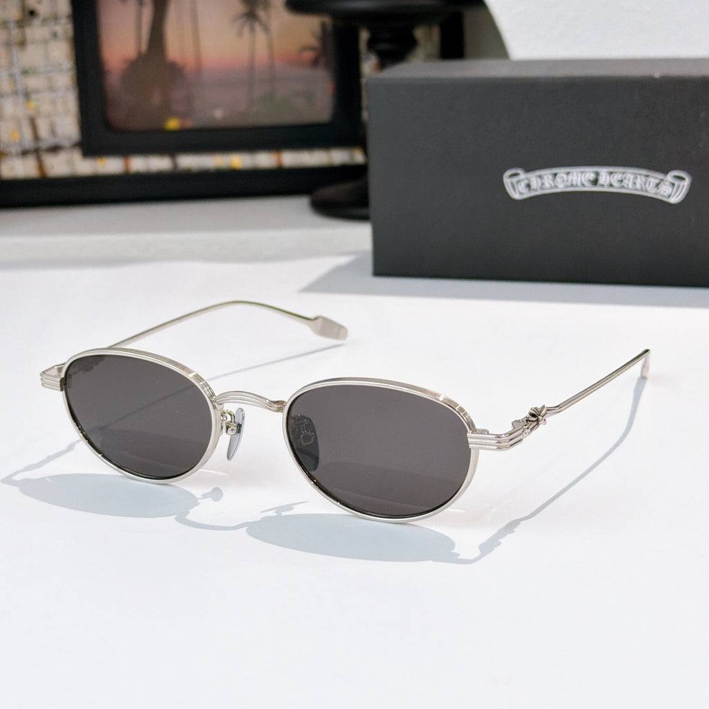 Round sunglasses with dark lenses and silver metal frame, decorative temple arms.