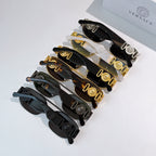 Assorted sunglasses collection with black frames and gold-tone accents, stacked view