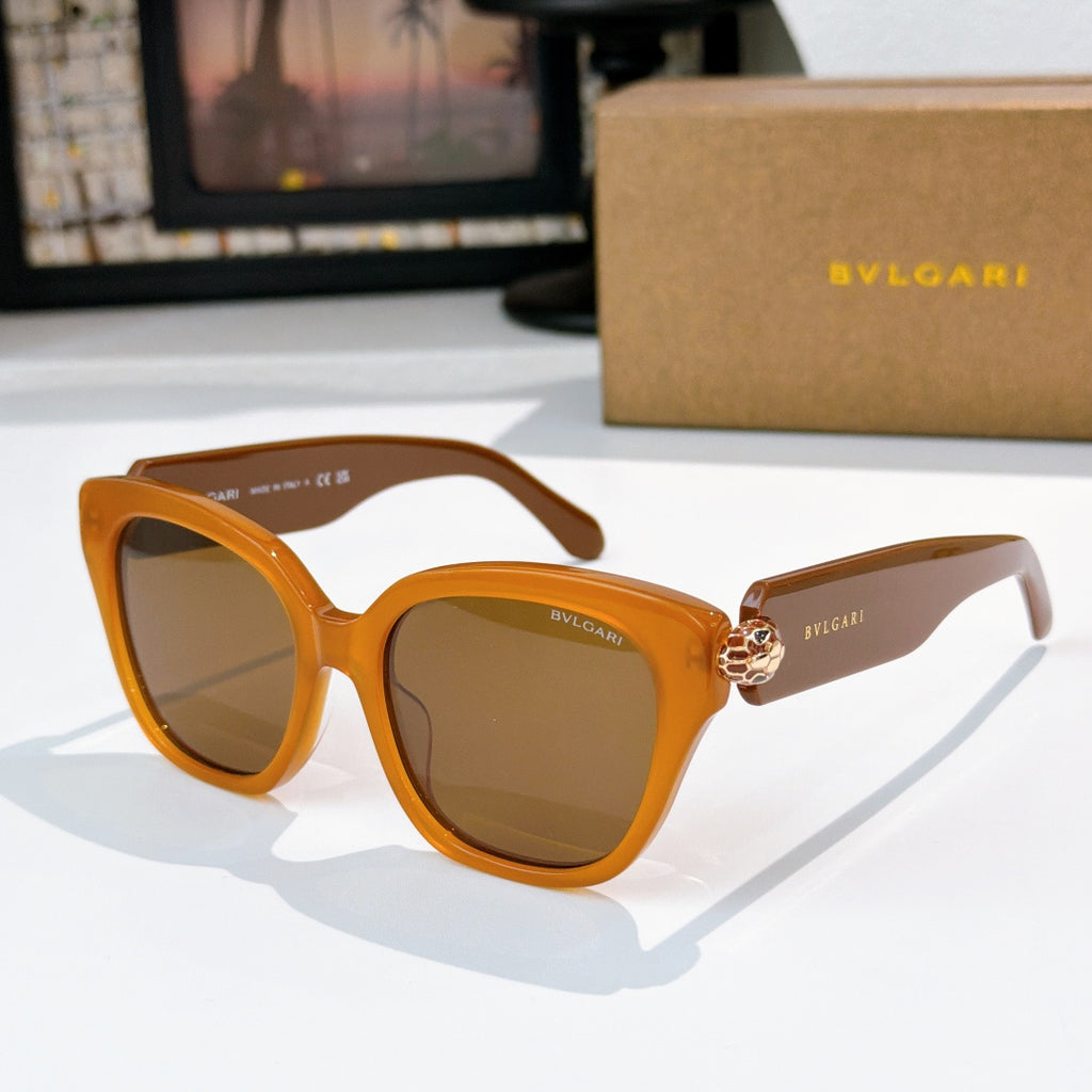 Cat-eye sunglasses with orange frames, brown tinted lenses, and gold-tone jewel bridge