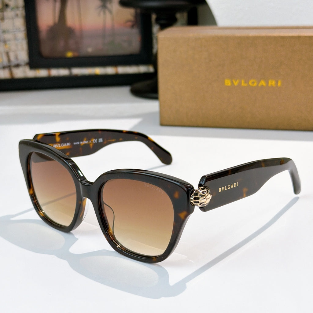 Cat-eye sunglasses with black frames, tan-brown lenses, and gold-tone jewel bridge