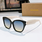 Cat-eye sunglasses with black frames, blue gradient lenses, and gold-tone jewel bridge