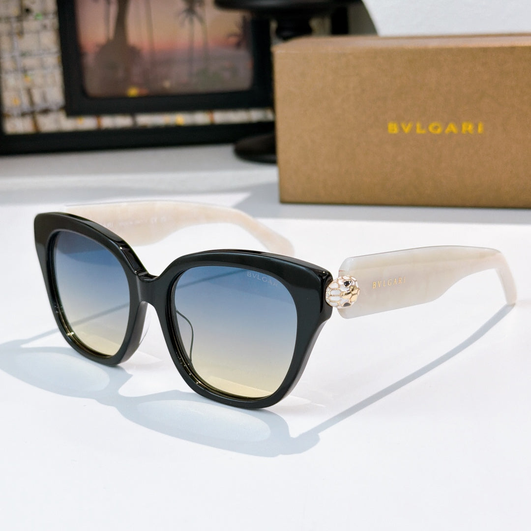 Cat-eye sunglasses with black frames, blue gradient lenses, and gold-tone jewel bridge