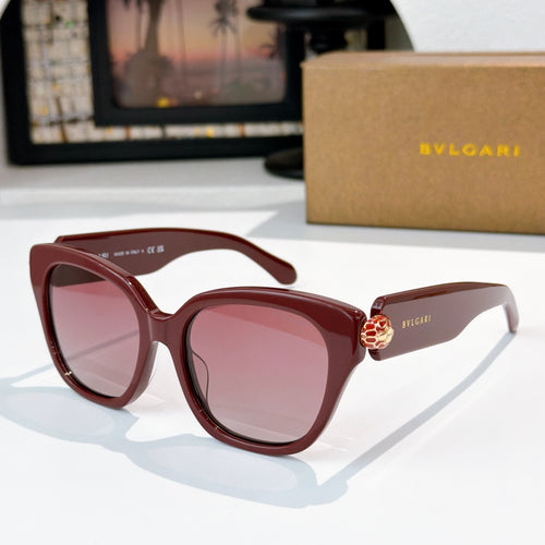 Cat-eye sunglasses with dark red frames, pink lenses, and gold-tone jewel at bridge