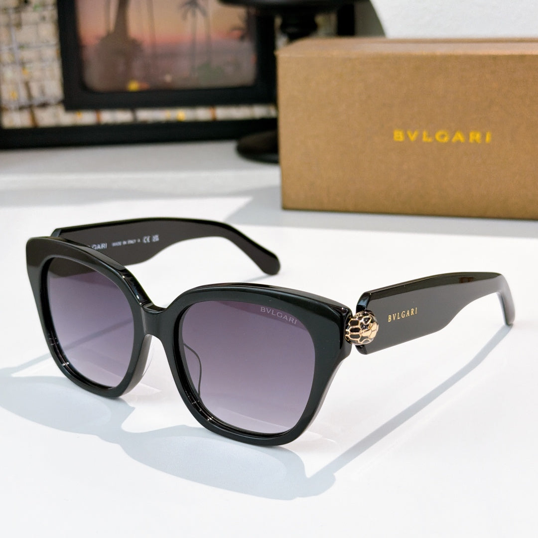 Cat-eye sunglasses with black frames, dark purple lenses, and gold-tone jewel bridge