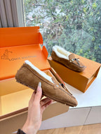 Brown suede shearling loafer, front view with stitched trim and metal charm detail