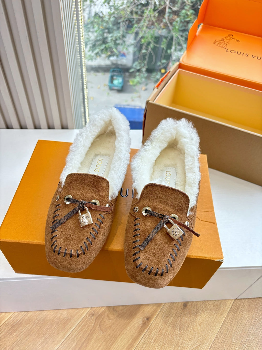 Pair of brown suede shearling loafers with lace-up ties and metal charm buckles