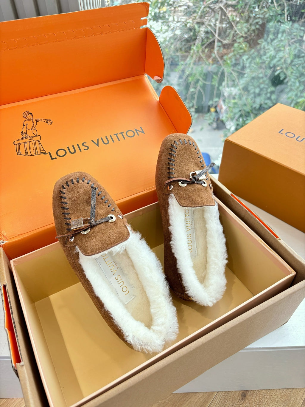 Brown suede shearling loafers with tie straps and stitched edges, shown from side