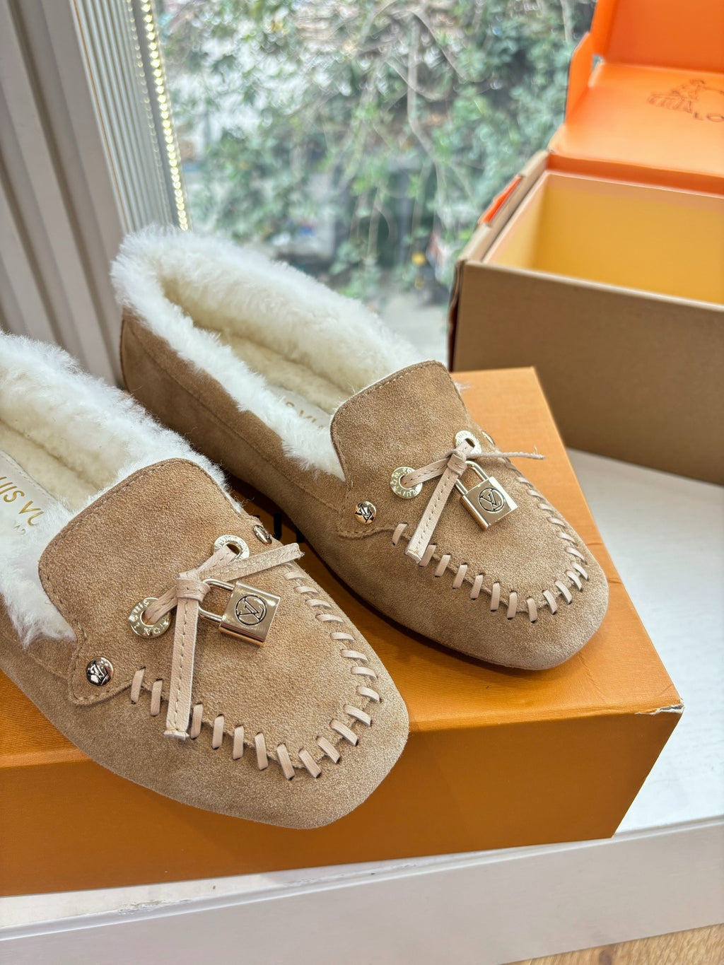 Unisex taupe suede moccasins with white shearling lining and tassel detail