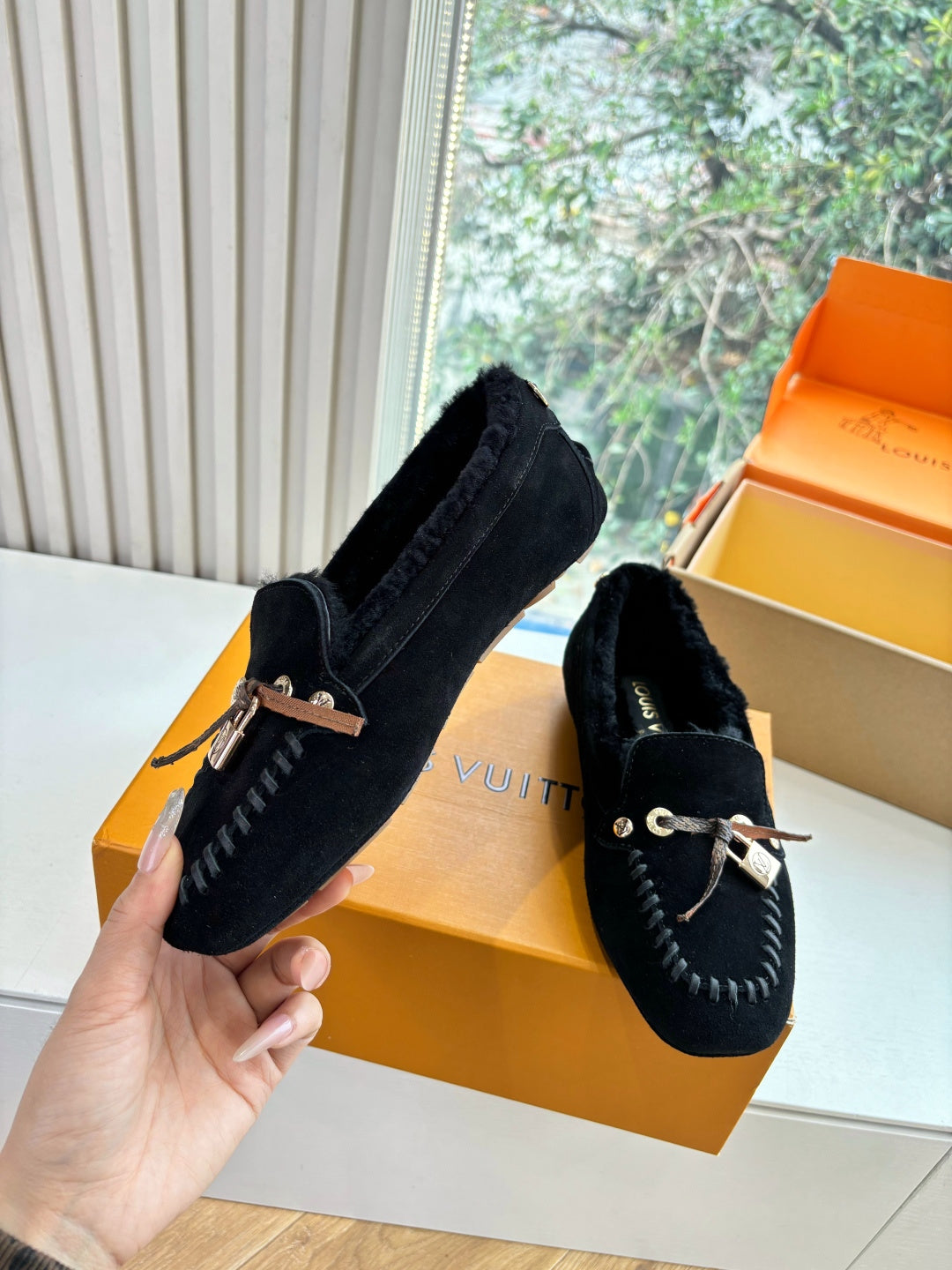 Black suede loafers, side profile, silver-tone lace detail with tassel.