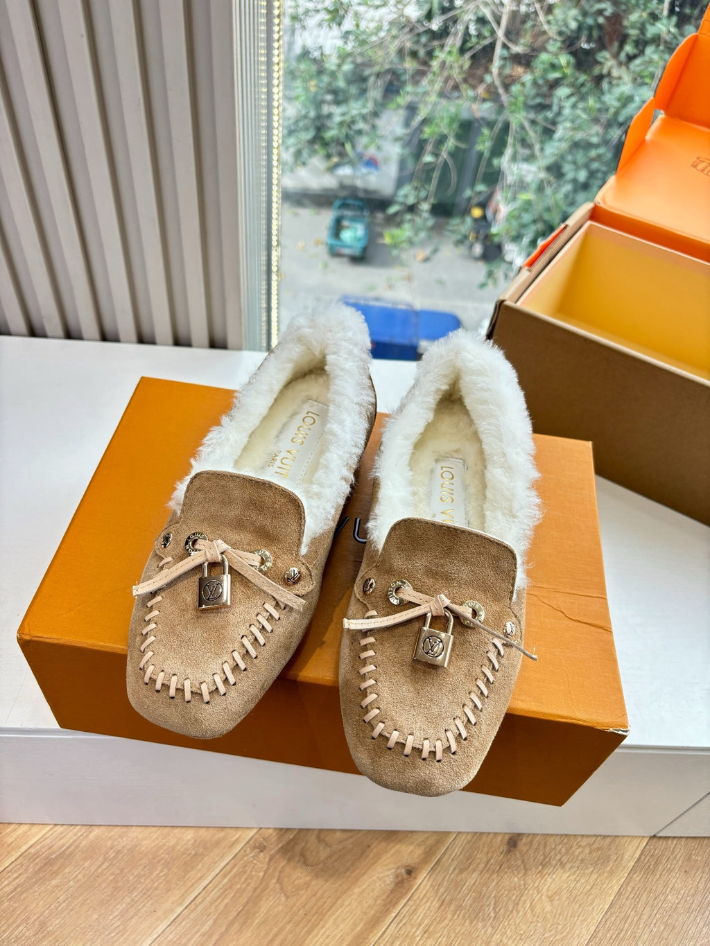 Pair of unisex taupe suede shearling loafers with bows in orange gift boxes