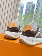 Back view of brown and white low-top sneakers with tan heel tab and LV-style emblem.