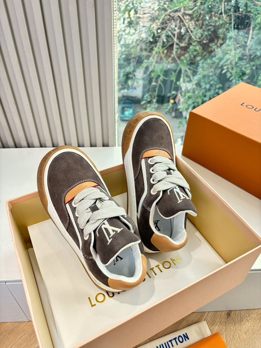 Pair of brown suede low-top sneakers with white stripes, LV-style tongue logo, gum soles.
