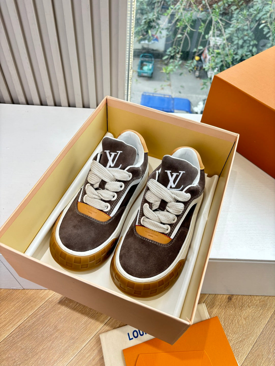 Brown and white low-top sneakers with LV-style side logo, tan heel, gum sole.