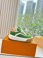 Green suede sneaker on orange display box, white laces and tan rubber sole