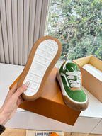 Green suede sneaker pair with outsoles visible, white laces and tan rubber soles