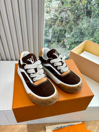 Brown suede sneakers with white laces, LV tongue logo, on orange presentation box.