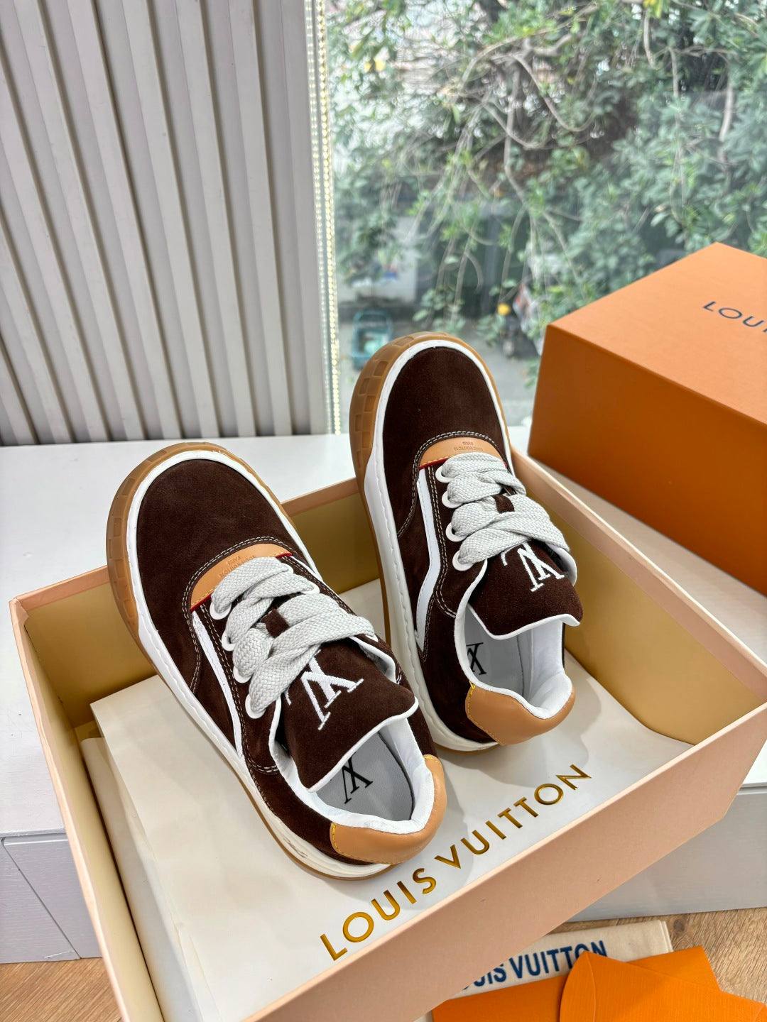 Brown suede sneakers with white rubber sole and LV logo on side, angled side view.