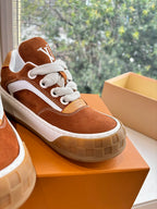 Close-up of brown suede sneaker with white laces and side LV emblem on box.