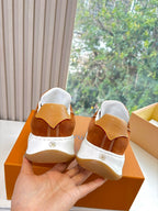 Back view of brown suede sneakers with white heel panels and hook-and-loop strap.