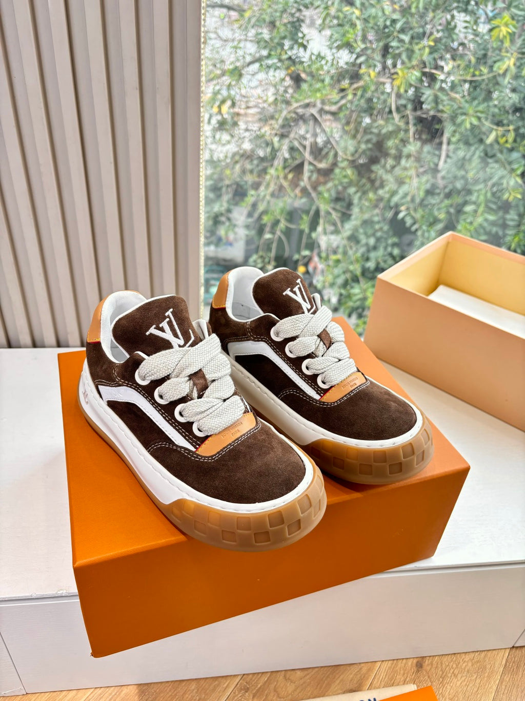 Brown and white low-top lace-up sneakers with white LV emblems