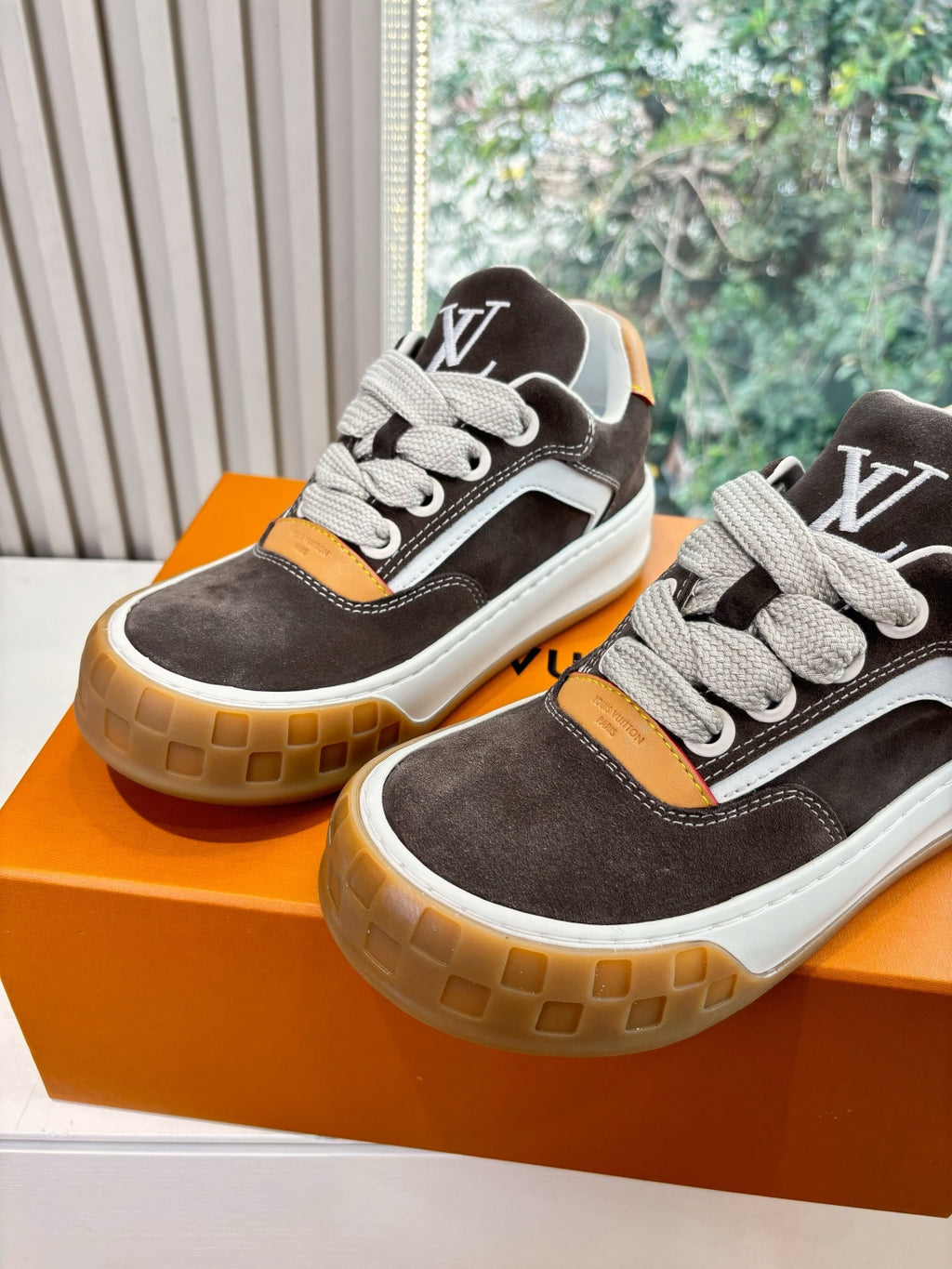 Two brown and white low-top sneakers with LV-style side logo, lace-up design, gum soles.