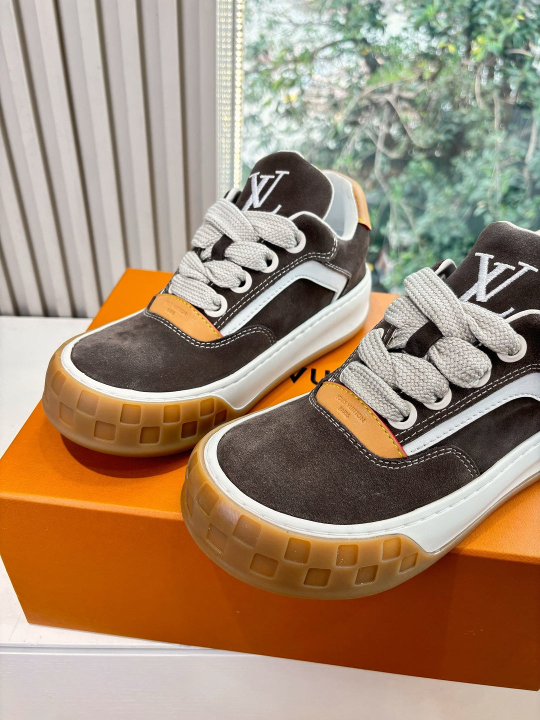 Two brown and white low-top sneakers with LV-style side logo, lace-up design, gum soles.