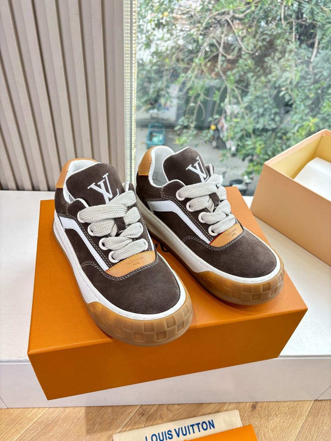 Brown and white lace-up sneakers with LV-style logo on tongue and side, gum soles.