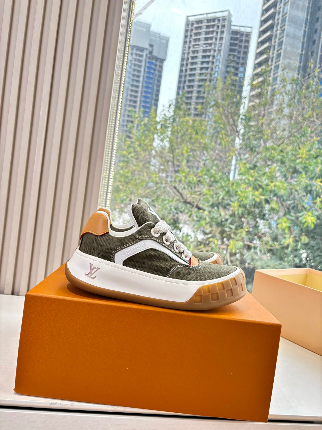 Unisex Louis Vuitton low-top sneakers, dark green canvas with white side stripe and gum sole.