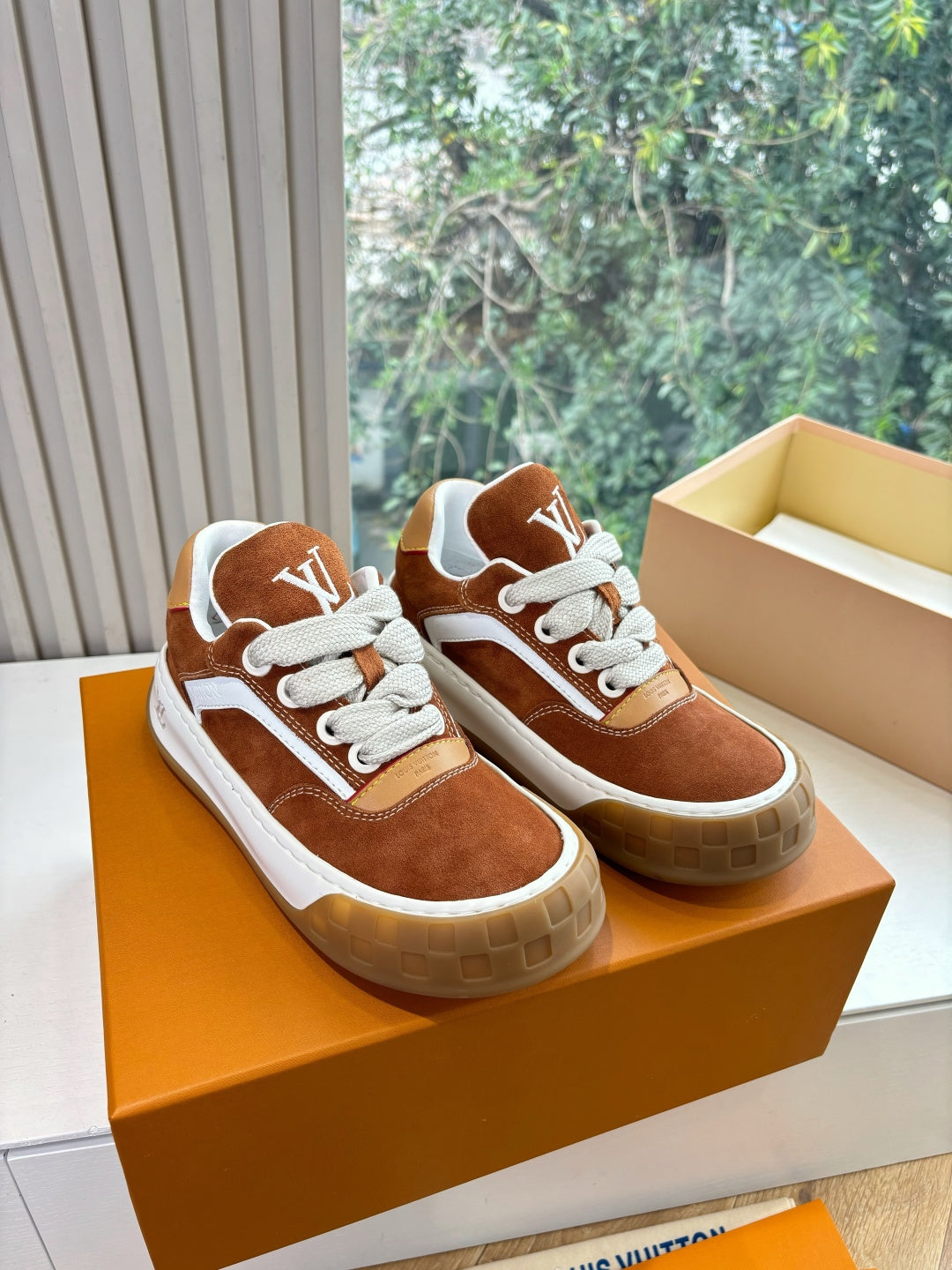 Pair of brown suede sneakers with white laces and LV logo on tan box.