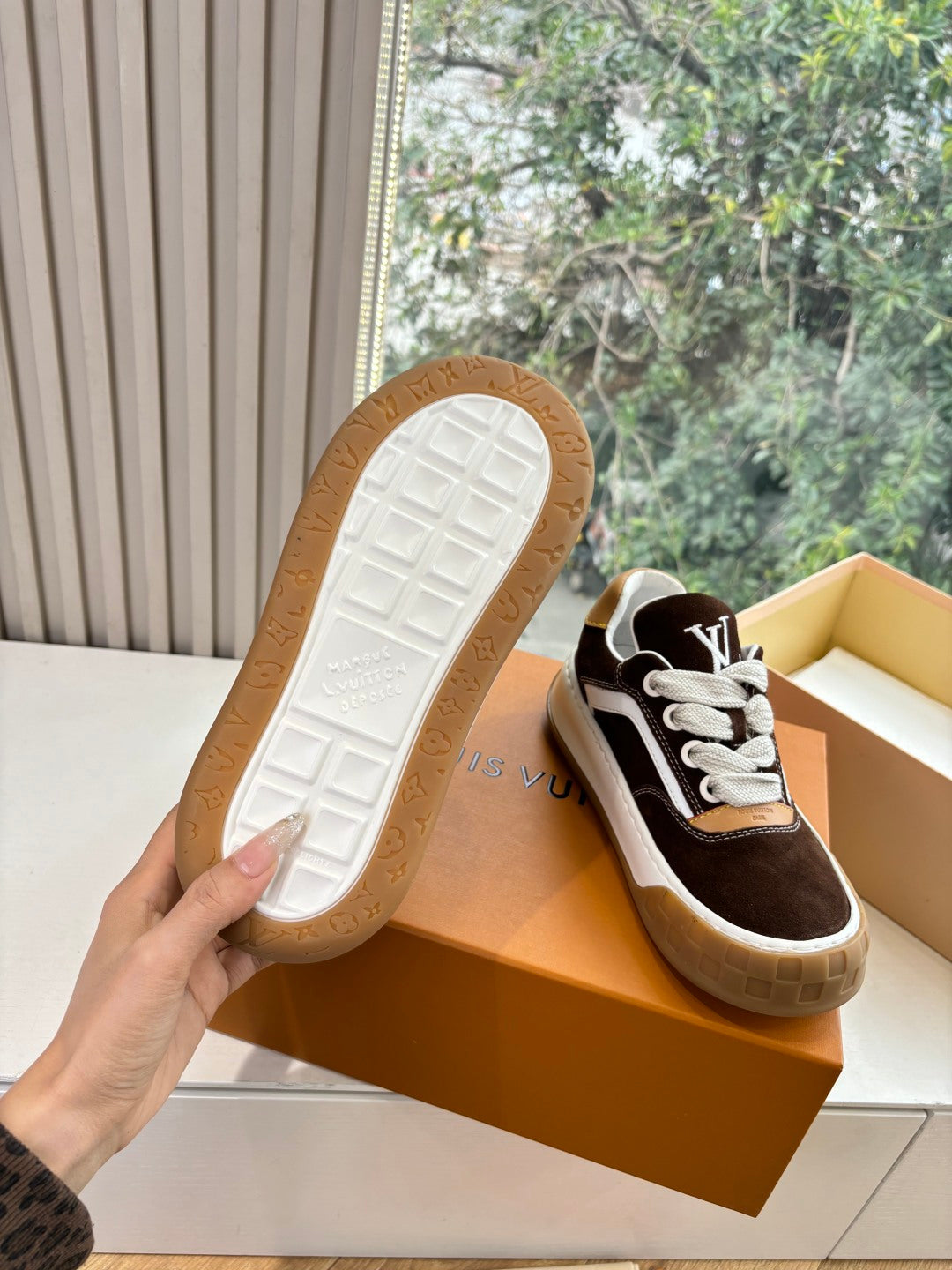 Sneakers outsole view: brown and white rubber tread with LV branding on bottom.
